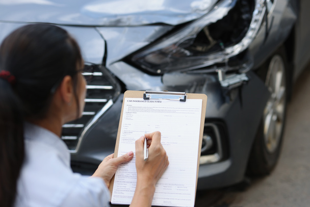 Vrouw verzekeringsagent vult verzekeringsformulier voor auto-schade na verkeersongeval - Foto, afbeelding