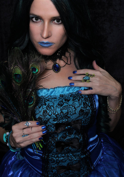 緑と黒の髪と孔雀の羽を持つブルーコルセットドレスの女性 - 写真・画像