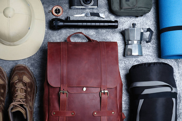 Flat lay composition with leather backpack and camping equipment for tourism on grey background - Zdjęcie, obraz