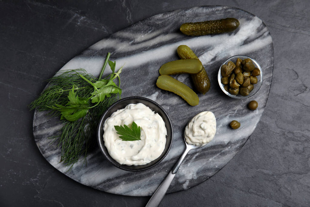 Tasty tartar sauce and ingredients on black table, top view - Фото, изображение