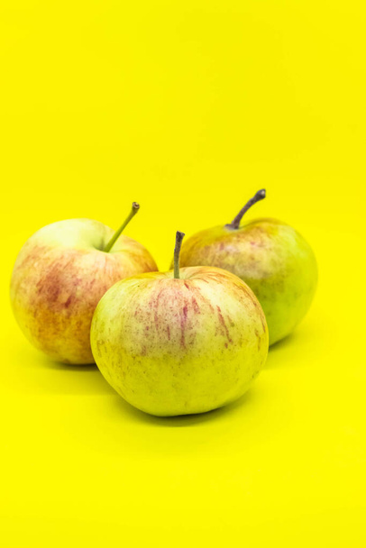 Три спелых сочных яблока на желтом фоне очень красивы - Фото, изображение
