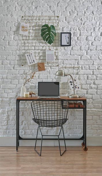 Salle de travail décorative avec mur de briques, chaise, ordinateur portable et bureau à domicile. Bureau en bois avec style lampe. - Photo, image