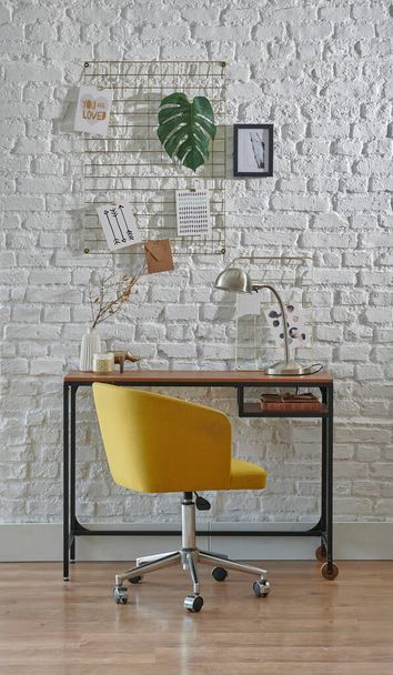 Dekoratives Arbeitszimmer mit Ziegelwand, Stuhl, Laptop und Home-Office-Stil. Holztisch mit Lampenstil. - Foto, Bild