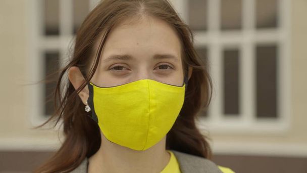 Взрослая школьница надевает маску и улыбается, пандемия 2022 года, фильтрует воздух для дыхательных путей легких, предотвращает инфекцию COVID-19, защищает человека от коронавируса в режиме маски - Фото, изображение