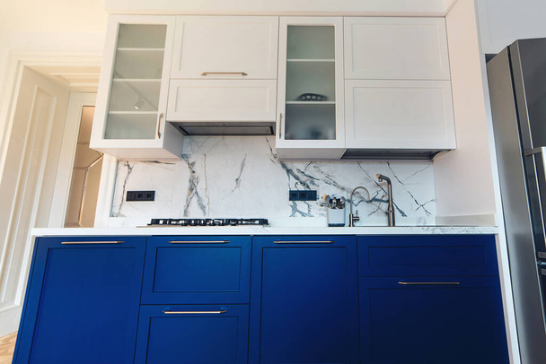Moderni keittiö puhdas sisustus. Ylellinen sininen ja valkoinen huonekalut keittiö marmori laatoitettu backsplash. Moderni uusi keittiö pesuallas, työtaso ja yksinkertainen kaapit. - Valokuva, kuva