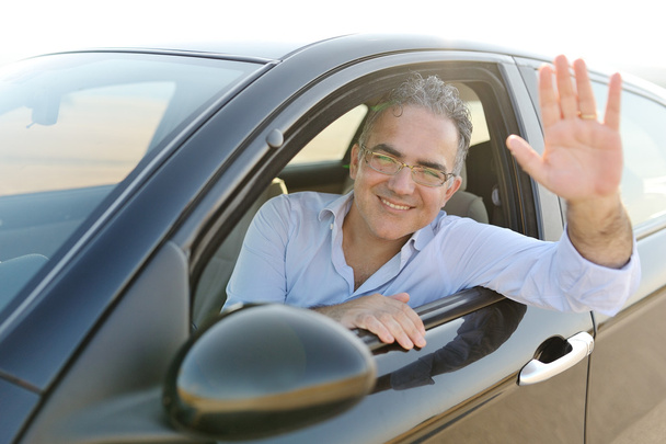 Hymyilevä mies istuu uudessa autossaan.
 - Valokuva, kuva