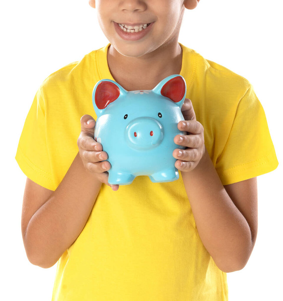 Funny portrait of little boy holding a blue moneybox isolated on a white background.  - Foto, immagini