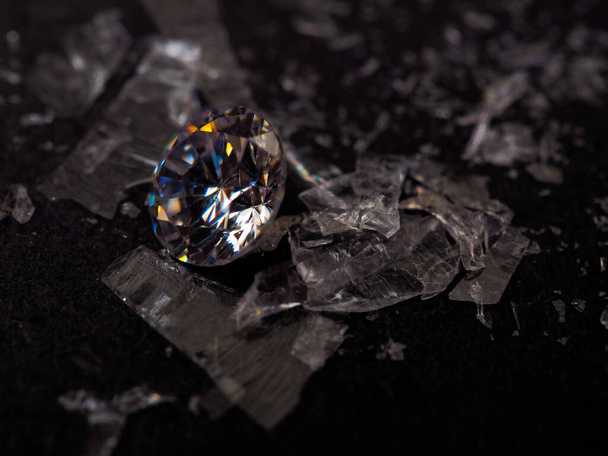 Close-up shot van roud gesneden zirkoon zirkonia edelstenen met gebroken glas omringd. Schieten op een zwarte achtergrond. - Foto, afbeelding