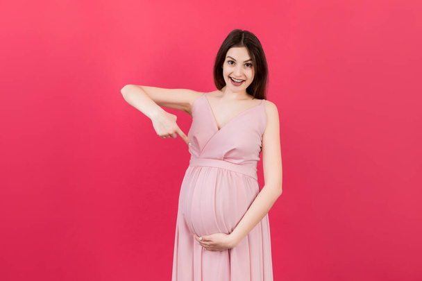 Junge Überraschung oder schockierte schwangere Frau isoliert farbigen Hintergrund. Ausdruck weiblich. - Foto, Bild