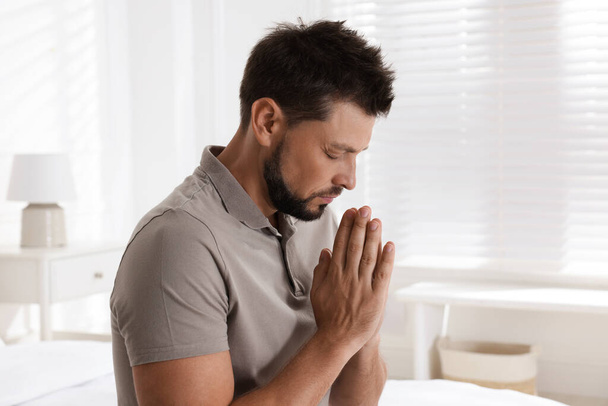Religious man with clasped hands praying at home - Photo, image