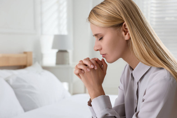 Religious young woman praying in bedroom. Space for text - Fotografie, Obrázek