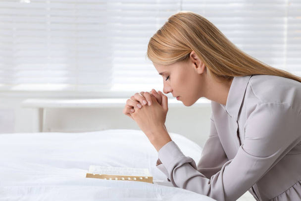 Θρησκευτική νεαρή γυναίκα με Βίβλο προσεύχεται στο υπνοδωμάτιο. Χώρος για κείμενο - Φωτογραφία, εικόνα