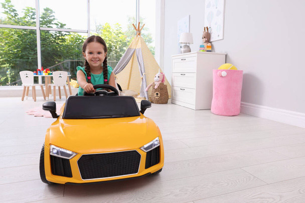 Adorable child driving toy car in room at home - Foto, Imagen