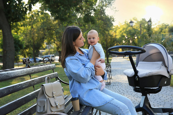 Young mother with her baby on bench in park - Foto, afbeelding