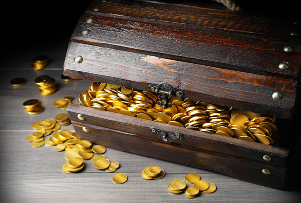 Open treasure chest with gold coins on grey wooden table, closeup  - Foto, imagen