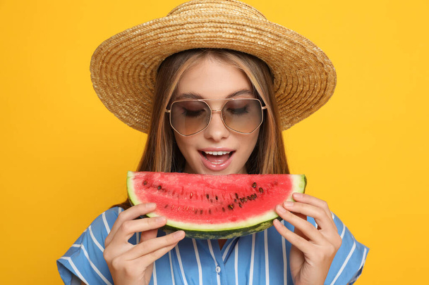 Beautiful girl with slice of watermelon on yellow background - Photo, Image