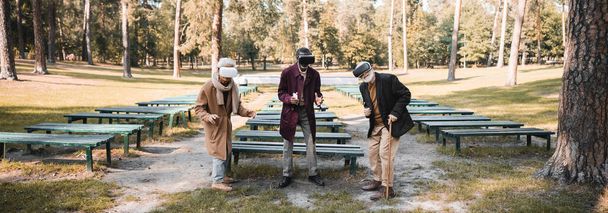 В осеннем парке размахивают гарнитурами мультиэтничные мужчины  - Фото, изображение