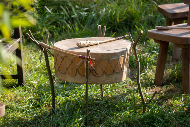 Североамериканский индийский барабан из роуайда с летучей мышью, готовой играть на лугу. - Фото, изображение