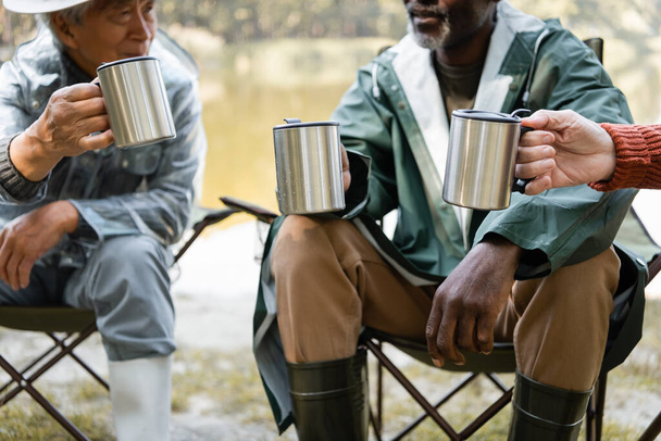 Thermo poháry v rukou různých starších mužů v rybářské oblečení venku  - Fotografie, Obrázek