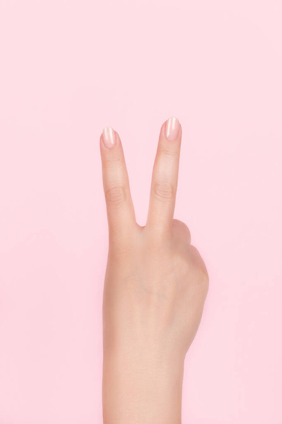 Female hand with nude nails making victory sign - Фото, изображение