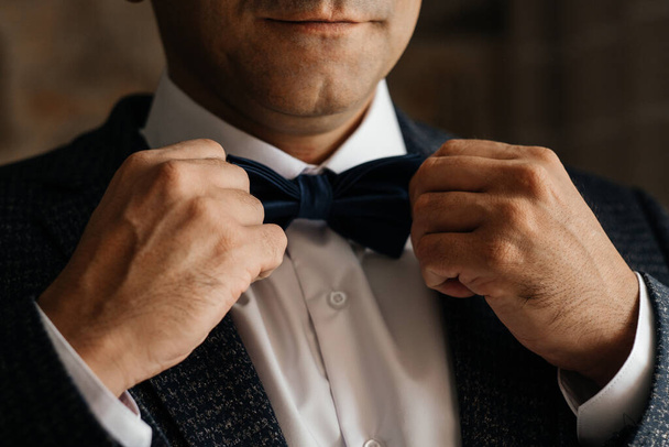 Morning preparation. The groom puts on a butterfly. Men's hands adjust the tie. - Photo, Image