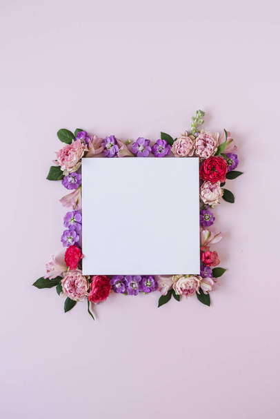 Frame made of rose flower buds on pink background and blank paper card sheet. Flat lay, top view. Copy space mockup. - 写真・画像