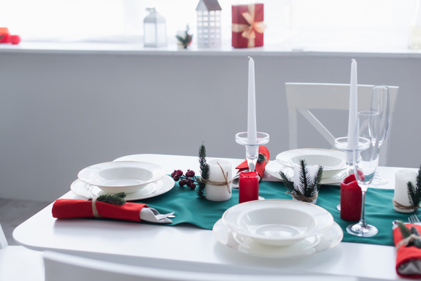 tafel met wit servies en kerstversiering geserveerd voor feestelijk diner - Foto, afbeelding