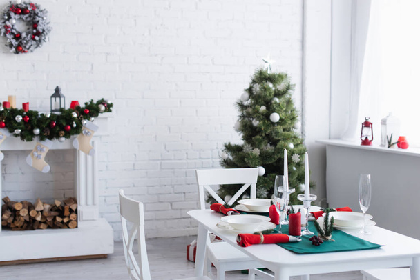 moderna sala de estar com lareira decorada, árvore de natal e mesa servida para o jantar festivo - Foto, Imagem