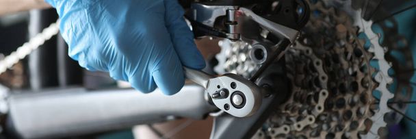 Gloved handyman fixing bicycle chain with tools closeup - Photo, Image