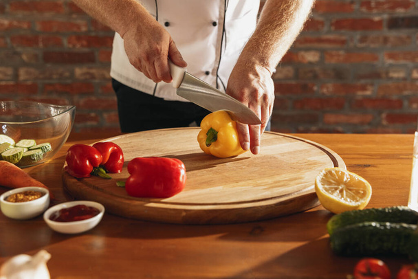 Close-up hands of male chef, cook cutting fresh vegetable salad in his cafe, restaurant kitchen. Concept of a correct, healthy diet. - Φωτογραφία, εικόνα