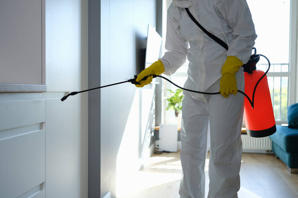Koruyucu tulumlu ve eldivenli işçiler apartmanı dezenfekte ediyor. - Fotoğraf, Görsel