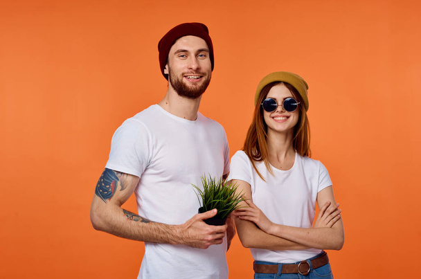 Tişörtlü komik adam ve kadın gençlik kıyafetleri turuncu arka plan - Fotoğraf, Görsel