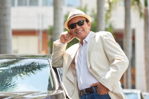 Портрет азиатского мужчины, опирающегося на автомобиль - Фото, изображение