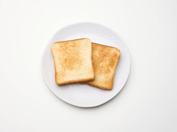 trozos cuadrados de pan tostado hecho de harina de trigo blanco en un plato redondo. Fondo mesa blanca - Foto, imagen