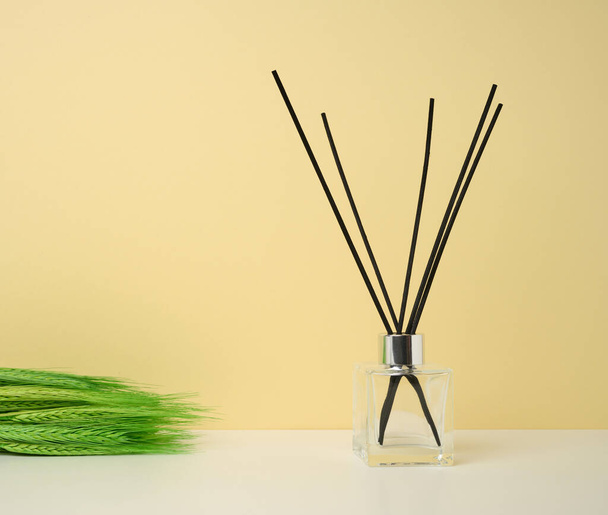 glass flask and wooden sticks, aroma lamp on colored background - Foto, Imagem