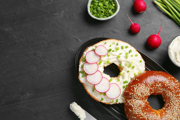 Delicious bagel with cream cheese, green onion and radish on black table, flat lay. Space for text - Foto, immagini