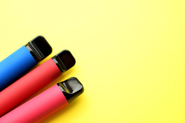 Three electronic cigarettes on a yellow background. Place for your text.  - Foto, Imagem