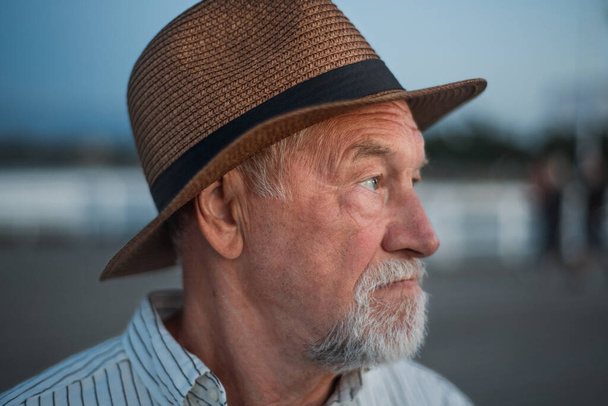 Portrait of senior man tourist loooking aside outdoors on pier by sea. - Foto, afbeelding