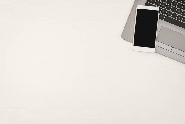 Widok z góry zdjęcie smartfona na laptopie na izolowanym białym drewnianym tle stołu z pustą przestrzenią - Zdjęcie, obraz