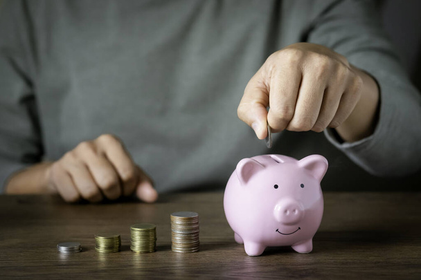 A man hand putting coin in pink piggy bank for account save money. Planning step up, saving money for future plan, retirement fund. Business investment-finance accounting concept. - Foto, immagini