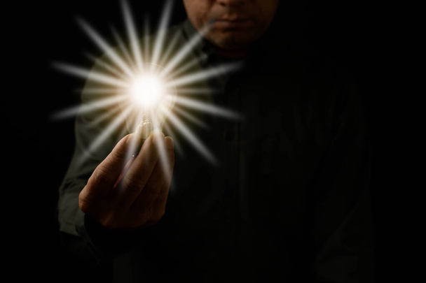 2022 New Year concept, A man holding a light bulb is the concept of the startup that drives global business. Bright lights give hope to small businesses. Closeup, Copy space, Black Blurred background - Photo, Image