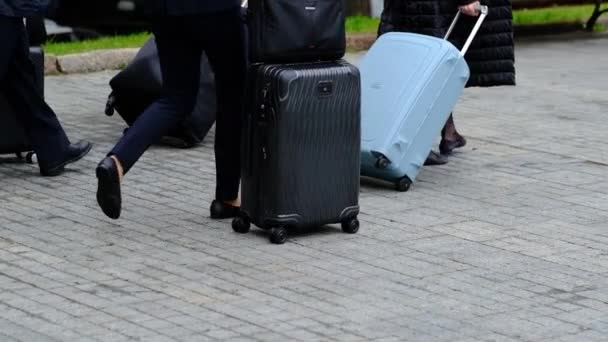 several people with luggage and suitcases are walking along the street. legs and suitcases in the frame - Footage, Video