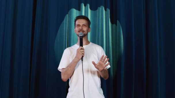 Fehér férfi fehér pólóban, mikrofonnal a kezében viccek, nevetés, beszéd - Felvétel, videó