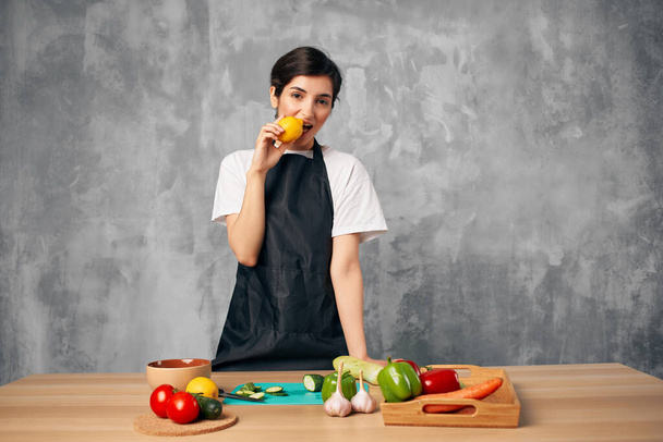 Mulher de avental preto na cozinha corte de legumes placa de corte - Foto, Imagem
