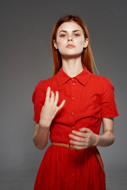 rudowłosa kobieta w czerwonej sukience pozująca w studio. Wysokiej jakości zdjęcie - Zdjęcie, obraz