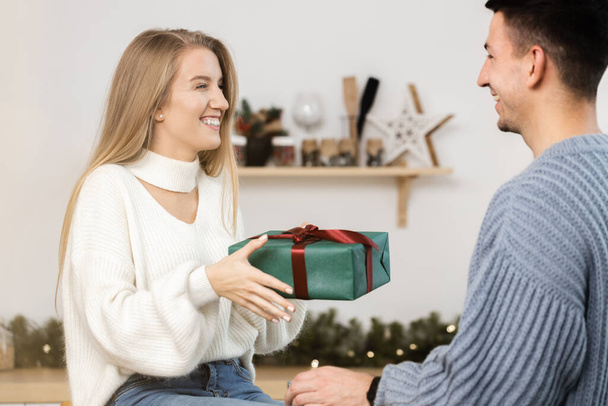 Sweet couple opening Christmas gifts in the living room at home - Fotoğraf, Görsel