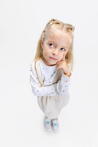 Top view portrait of little Caucasian girl, child posing isolated over white studio background. Thinking - Foto, Imagen