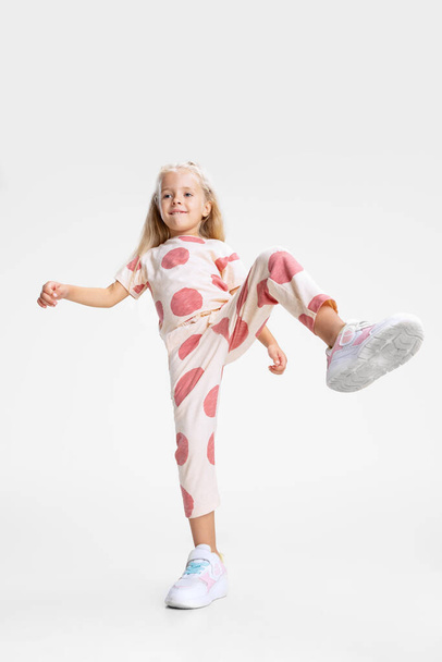 Πορτραίτο του μικρού καυκάσιου κοριτσιού, παιδί που ποζάρει απομονωμένο σε λευκό φόντο στούντιο. Σε κίνηση - Φωτογραφία, εικόνα