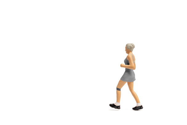 Μινιατούρα άτομα, Γυναίκα σε καλή φυσική κατάσταση φθορά τρέχει σε λευκό φόντο και χώρο για κείμενο - Φωτογραφία, εικόνα