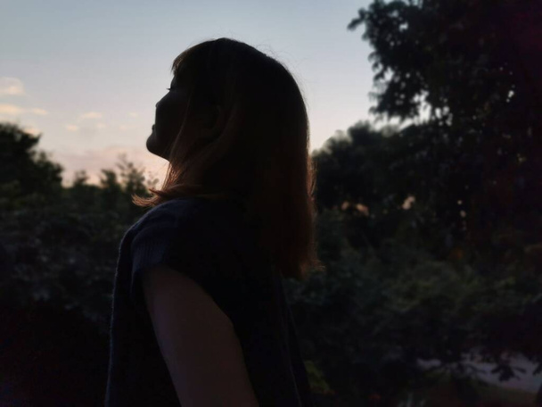 young woman in black dress with a backpack on the background of the sunset - Φωτογραφία, εικόνα